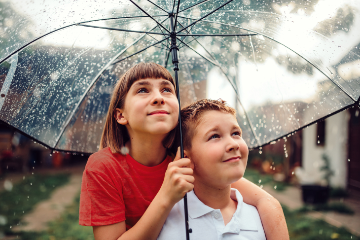 Sibllings sharing umbrella